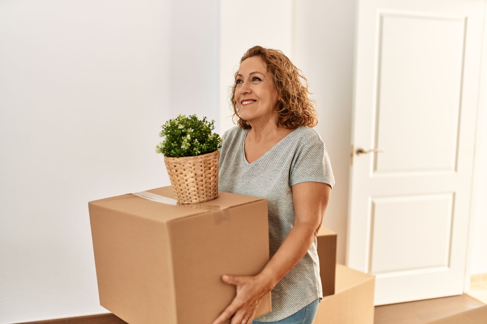 A woman carries a box of her parent's belongings into an assisted living apartment.