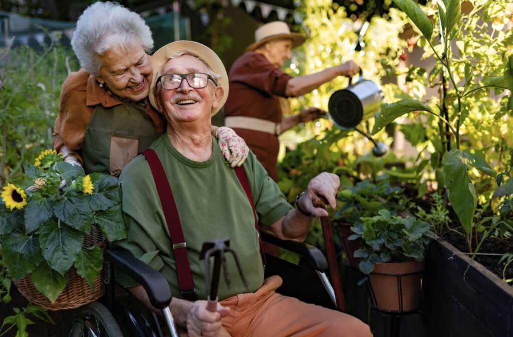 Three seniors with dementia enjoy spending time together in a communal garden in memory care to support their well-being